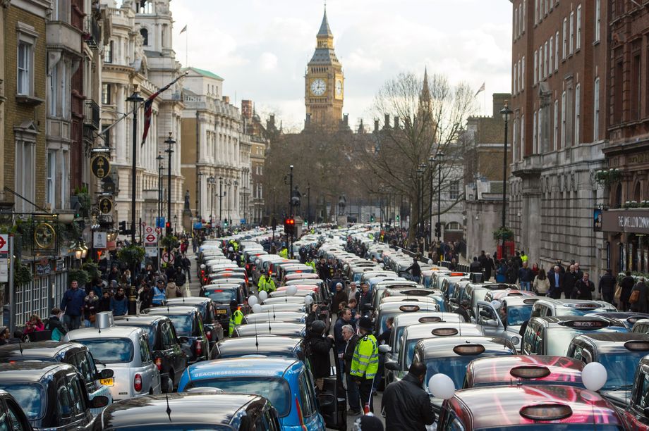 Компании-платформы постоянно меняют условия труда, вводя новые правила, к которым должны на ходу адаптироваться сотрудники. На фото – забастовка британских таксистов против Uber.